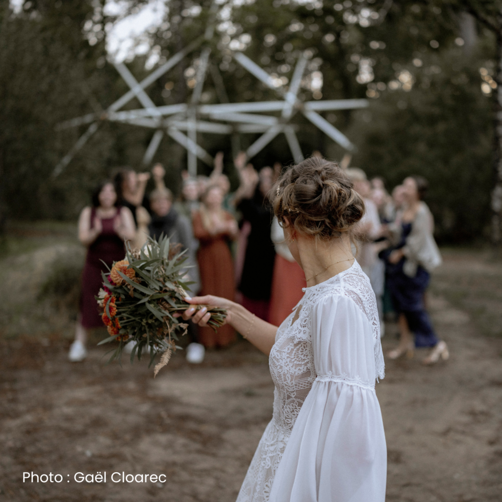 Mariée lançant son bouquet à ses invités lors d'une cérémonie de mariage en extérieur en Morbihan